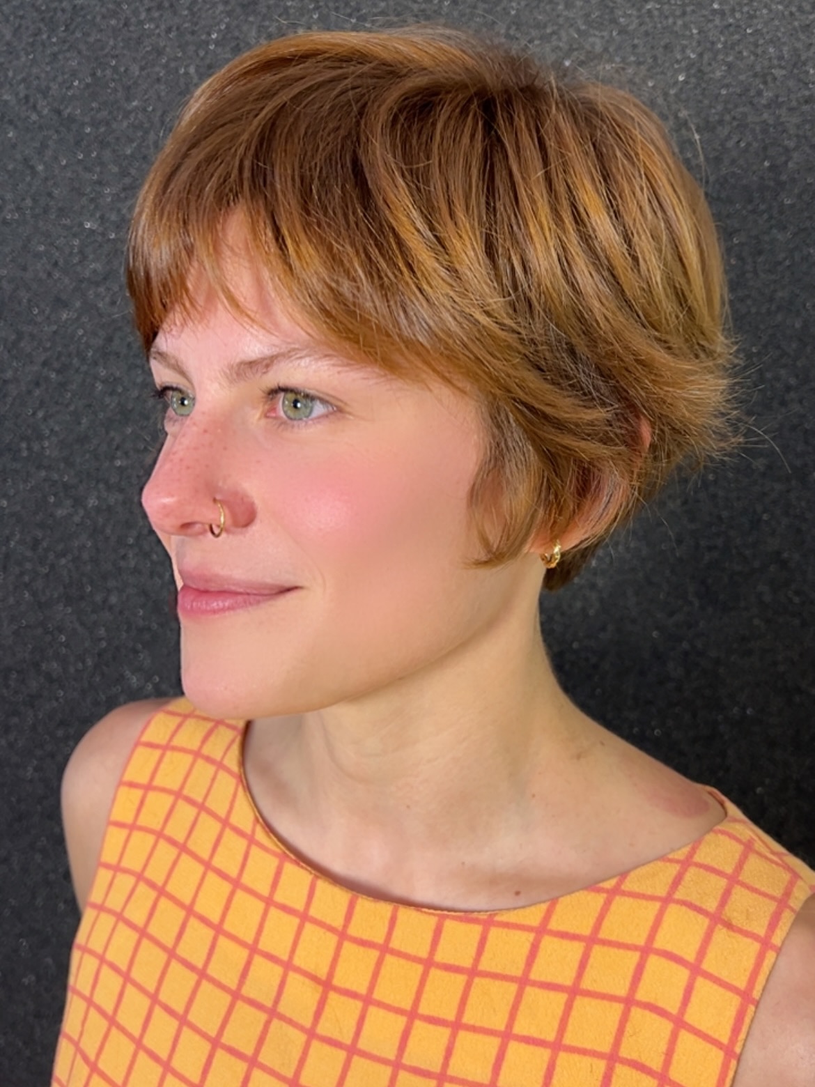 Warm copper pixie with short fringe, crown layers, and soft nape.