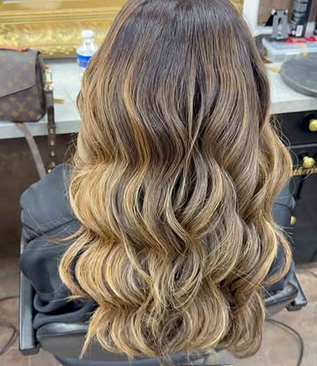 Back view of long wavy layers with blonde highlights.