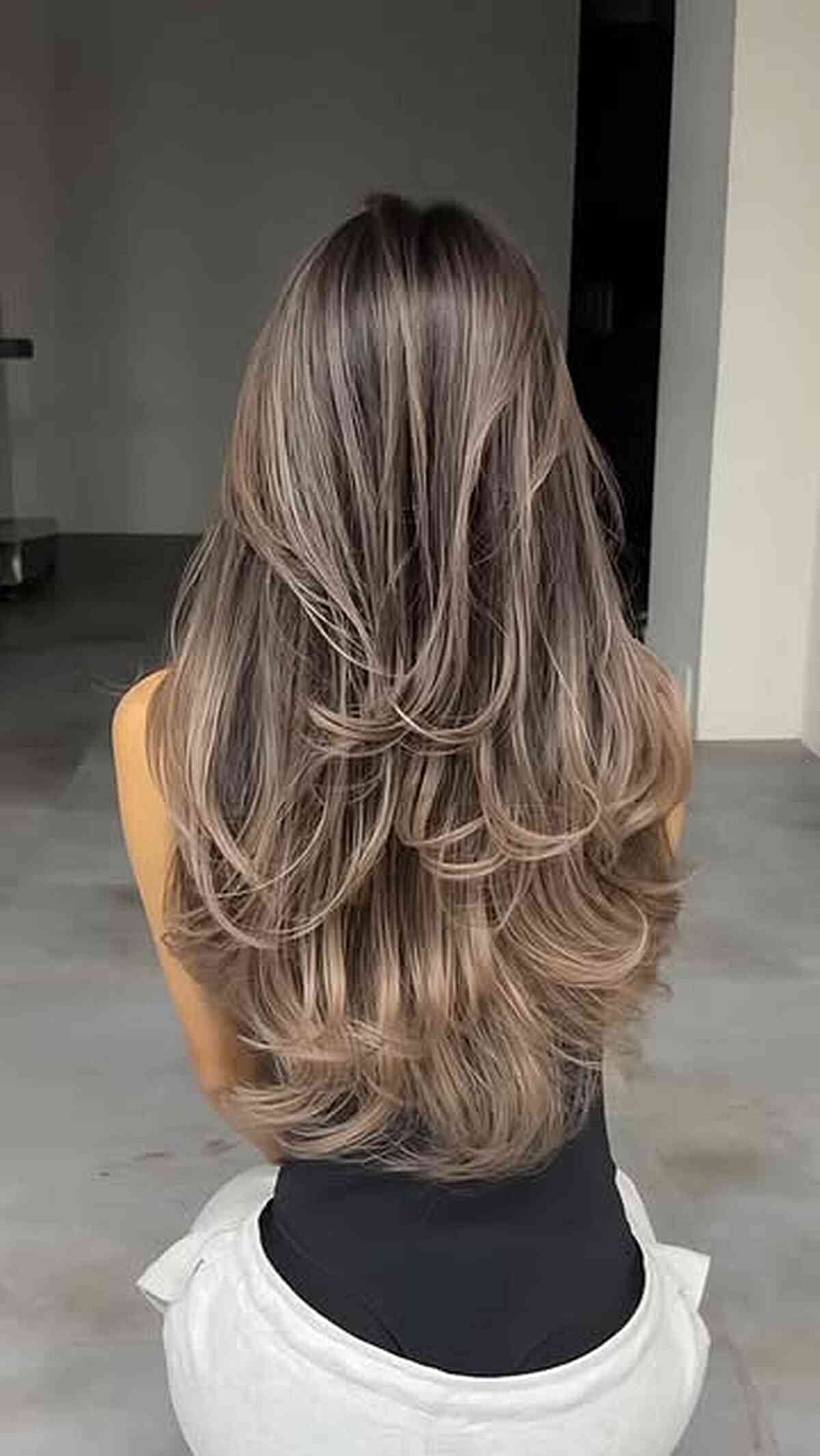Ash beige layered blowout with long, flipped ends.