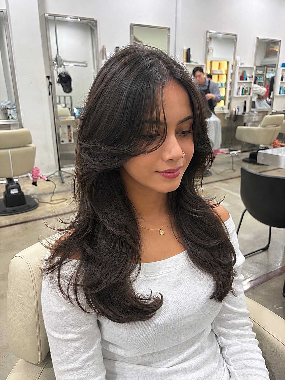 Long dark layered hair with a side-swept front and feathered ends.