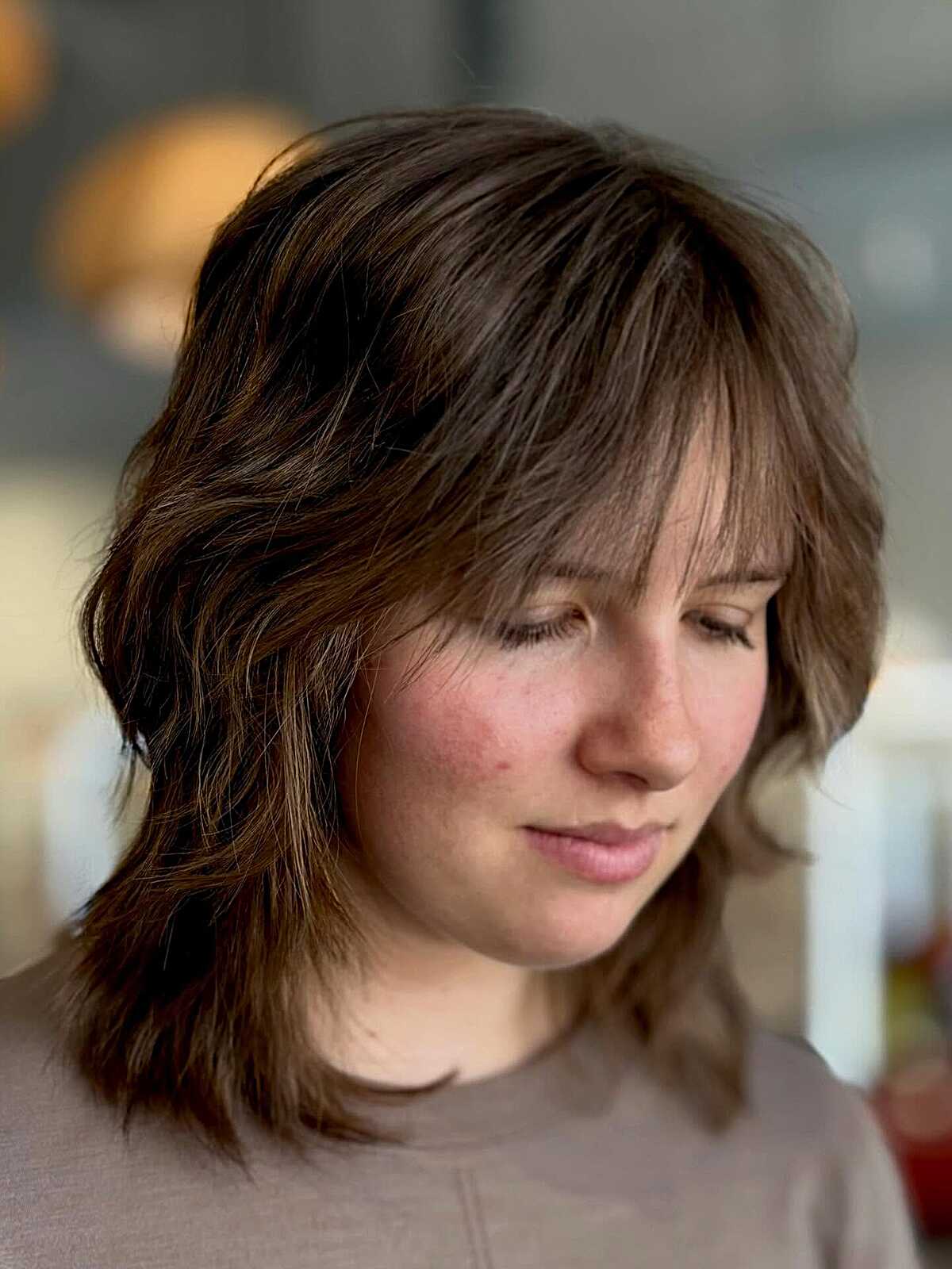 Tousled brunette shag with wispy bangs and layered ends.