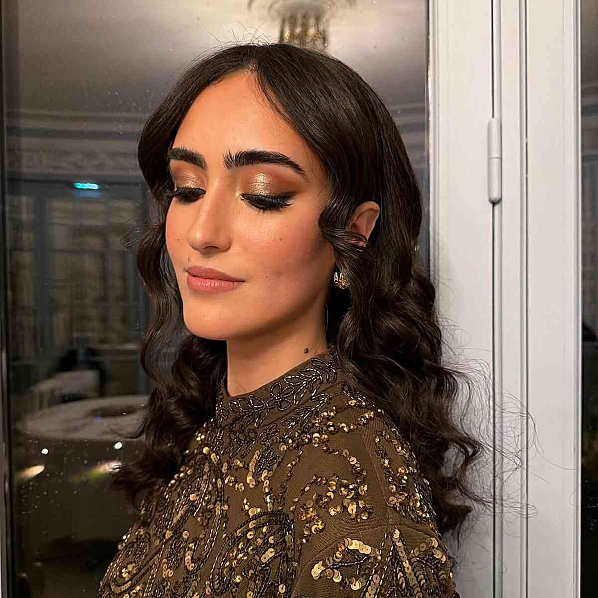 Dark wavy hair with face-framing pieces and a center part.