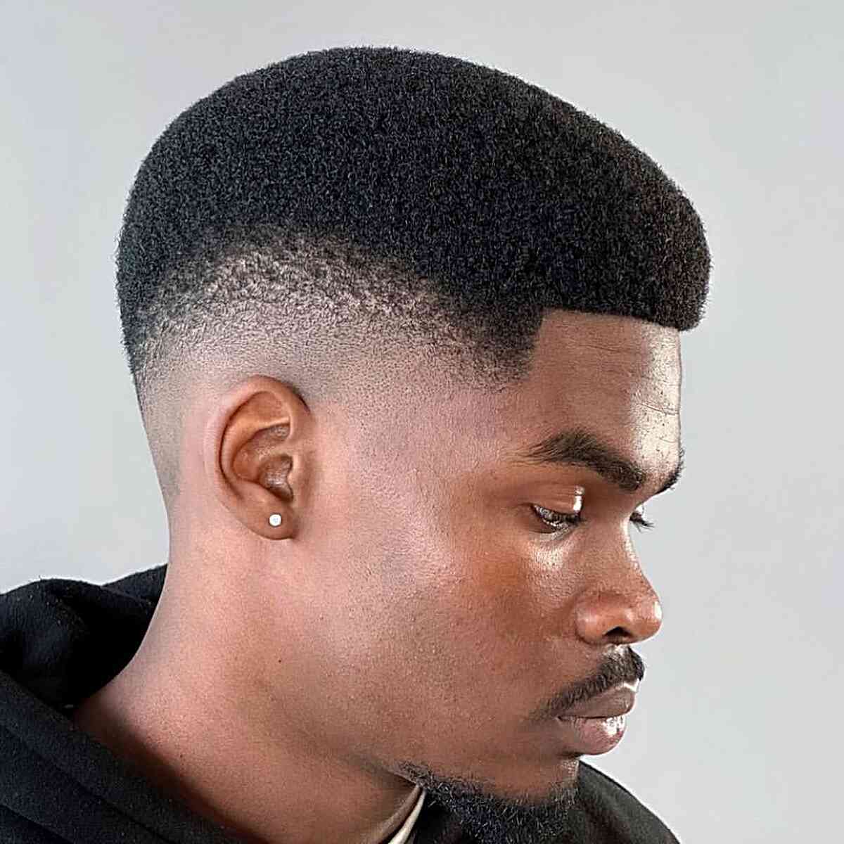 Short rounded top with a low skin fade and crisp edges.