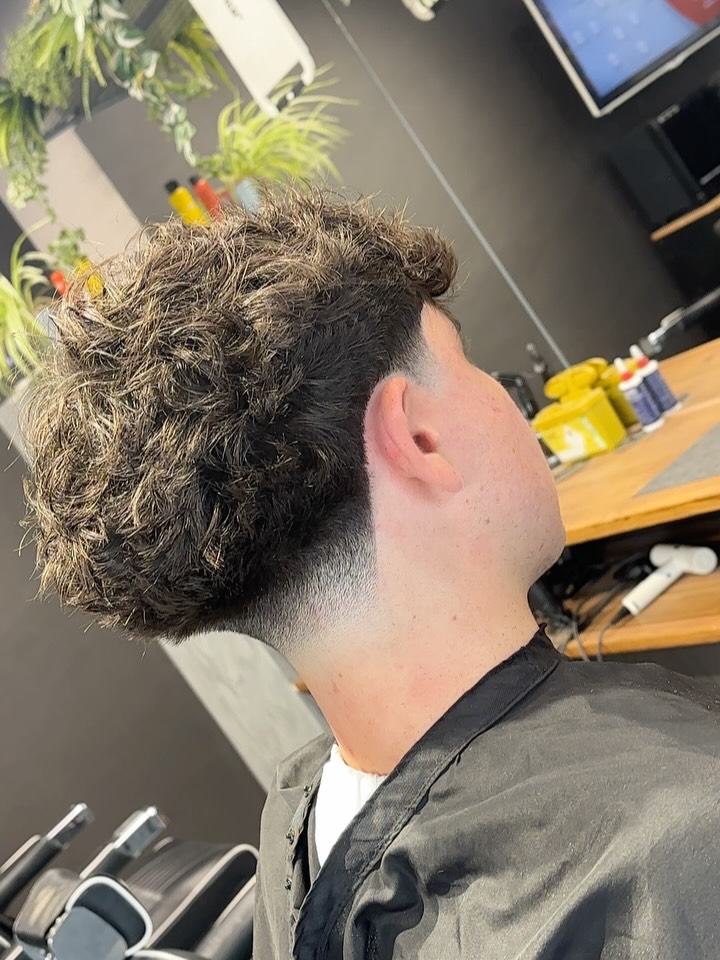 Full curly top with sharp side fade and tapered neck.