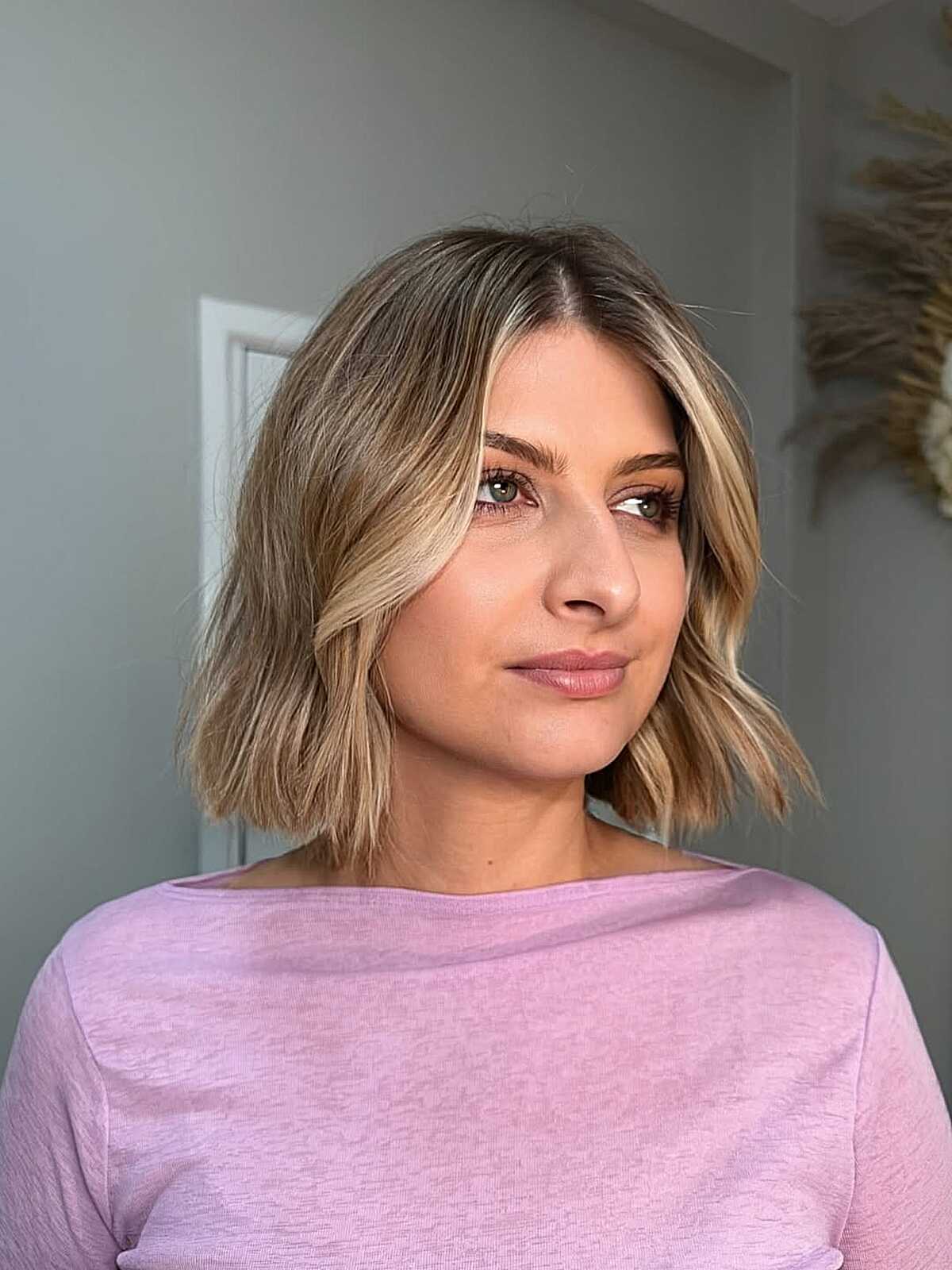 Sandy blonde bob with loose waves, center part, and brighter front pieces.