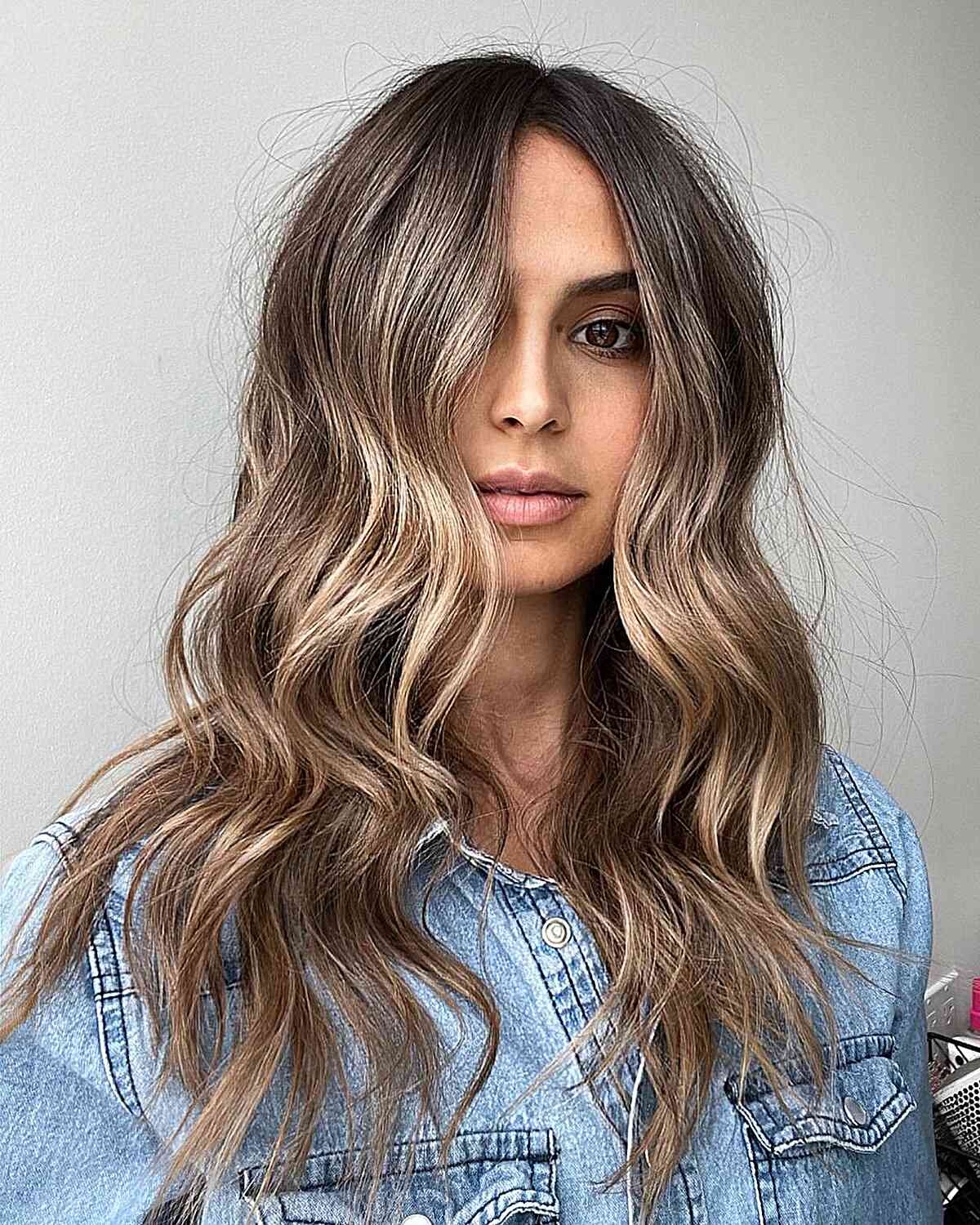 Medium-long bronde waves with soft blonde highlights over brunette hair.