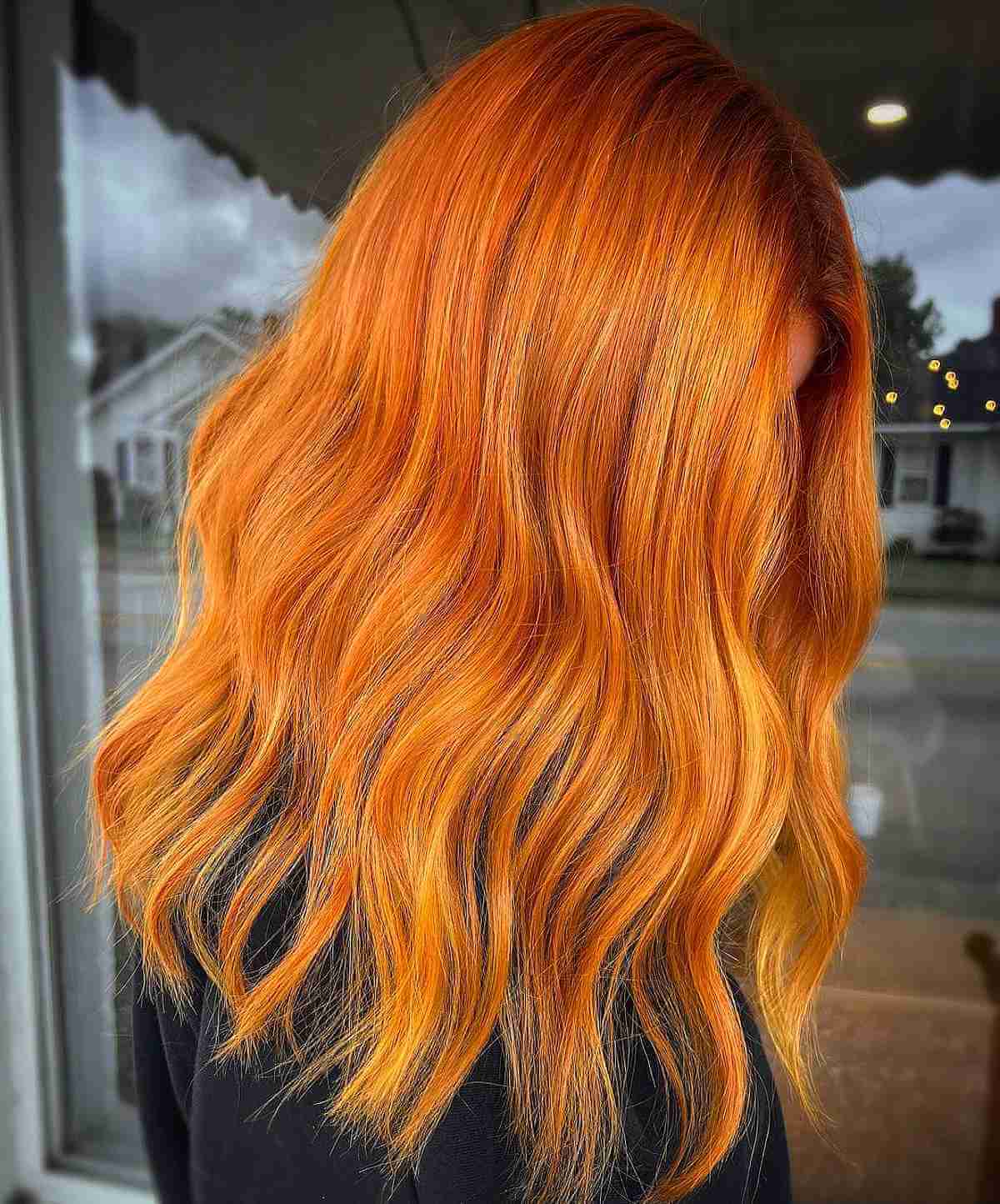 Long copper hair with loose waves and bright golden-orange highlights.