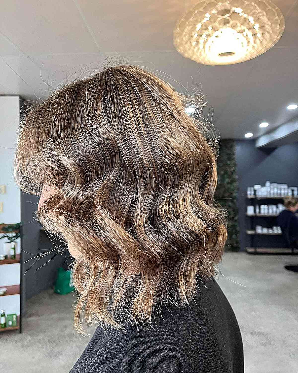 Shoulder-length bronde balayage with soft waves and lighter ends.