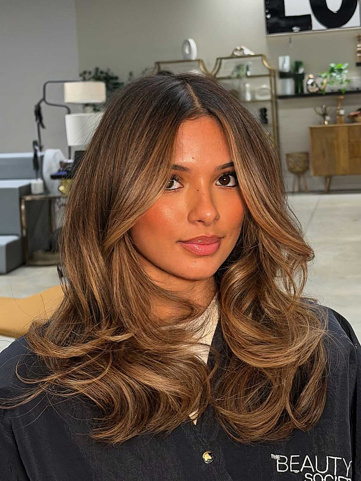 Long warm bronde layers with blown-out waves and caramel tones.