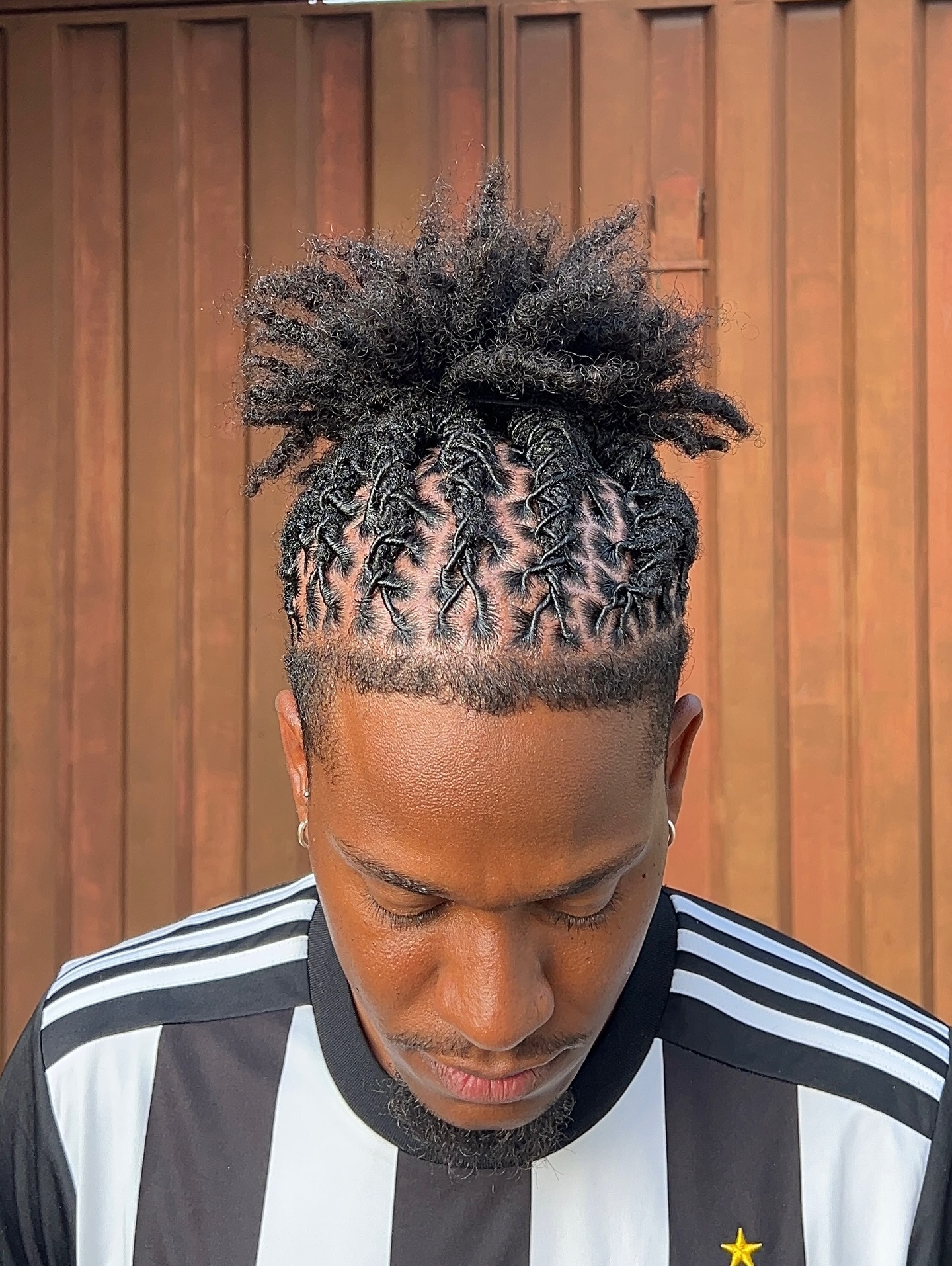 High bun made from long locs with braided sides and a fade.