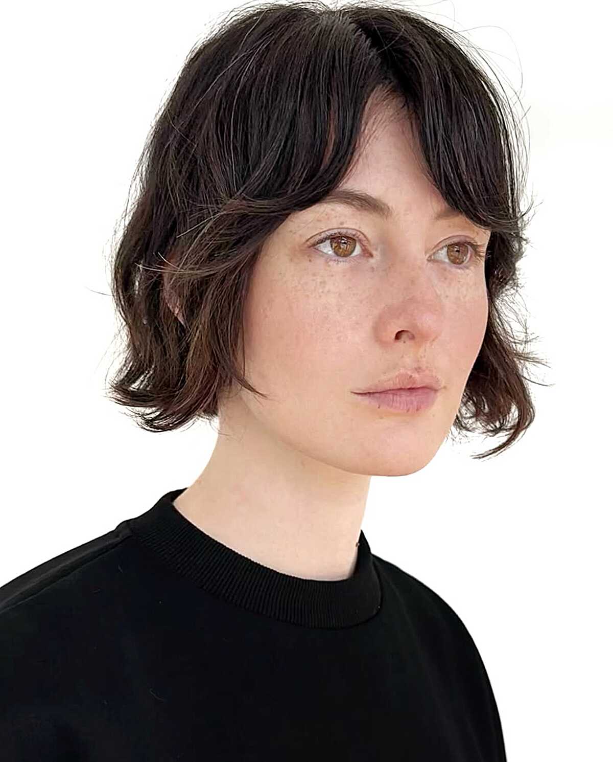 Dark brunette wavy bob with wispy bangs and softly flipped ends