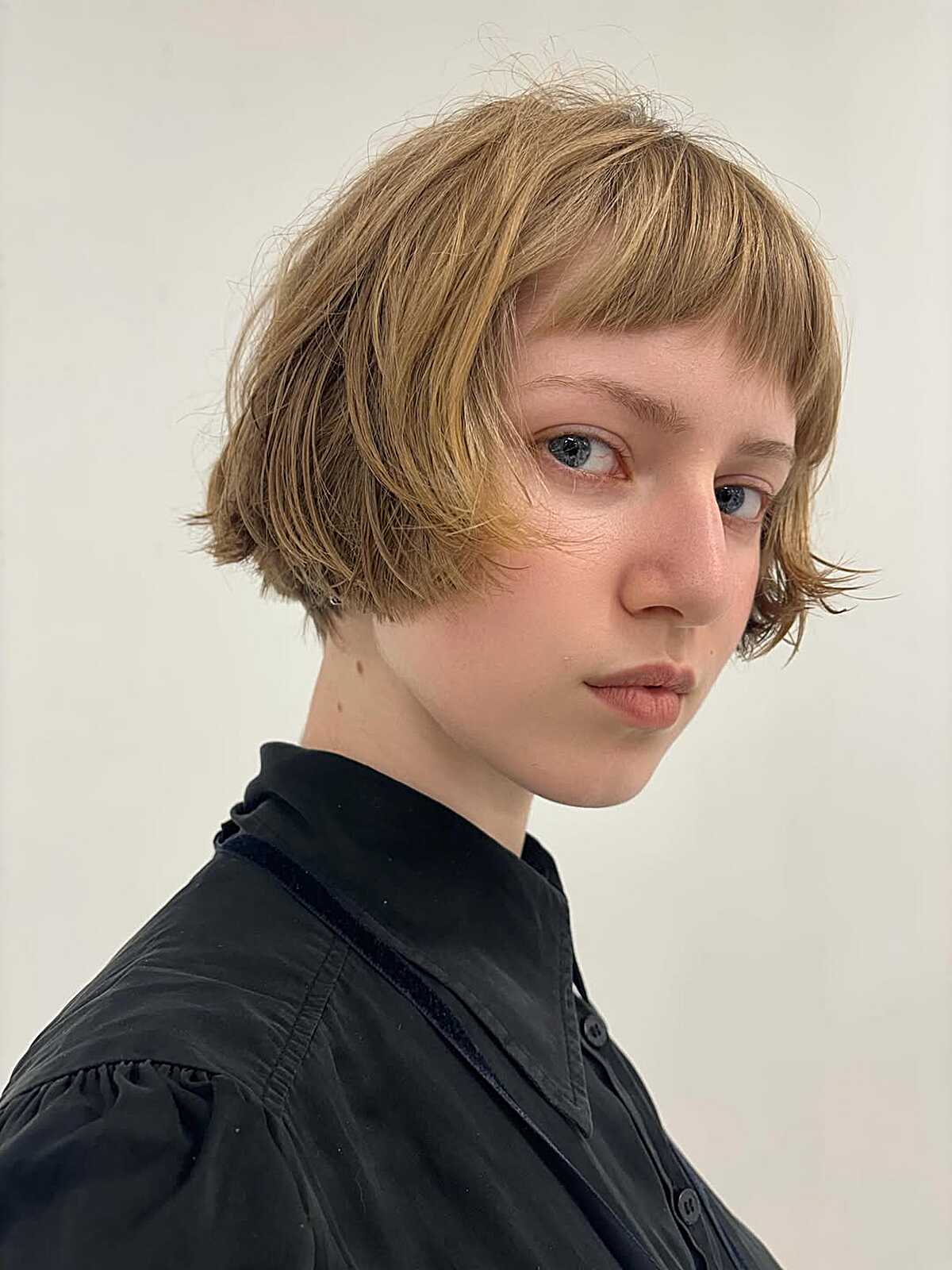 Golden blonde ear-length bob with wispy fringe and soft ends