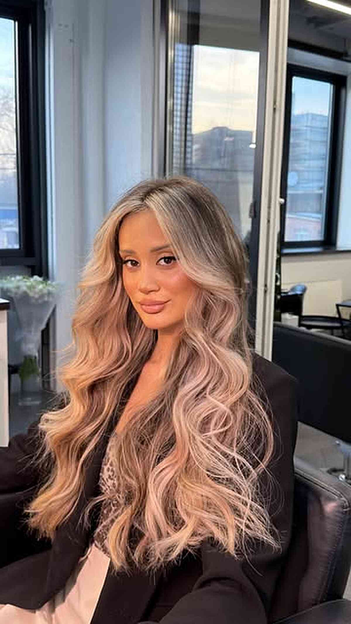 Long beige blonde waves with balayage and a center part.