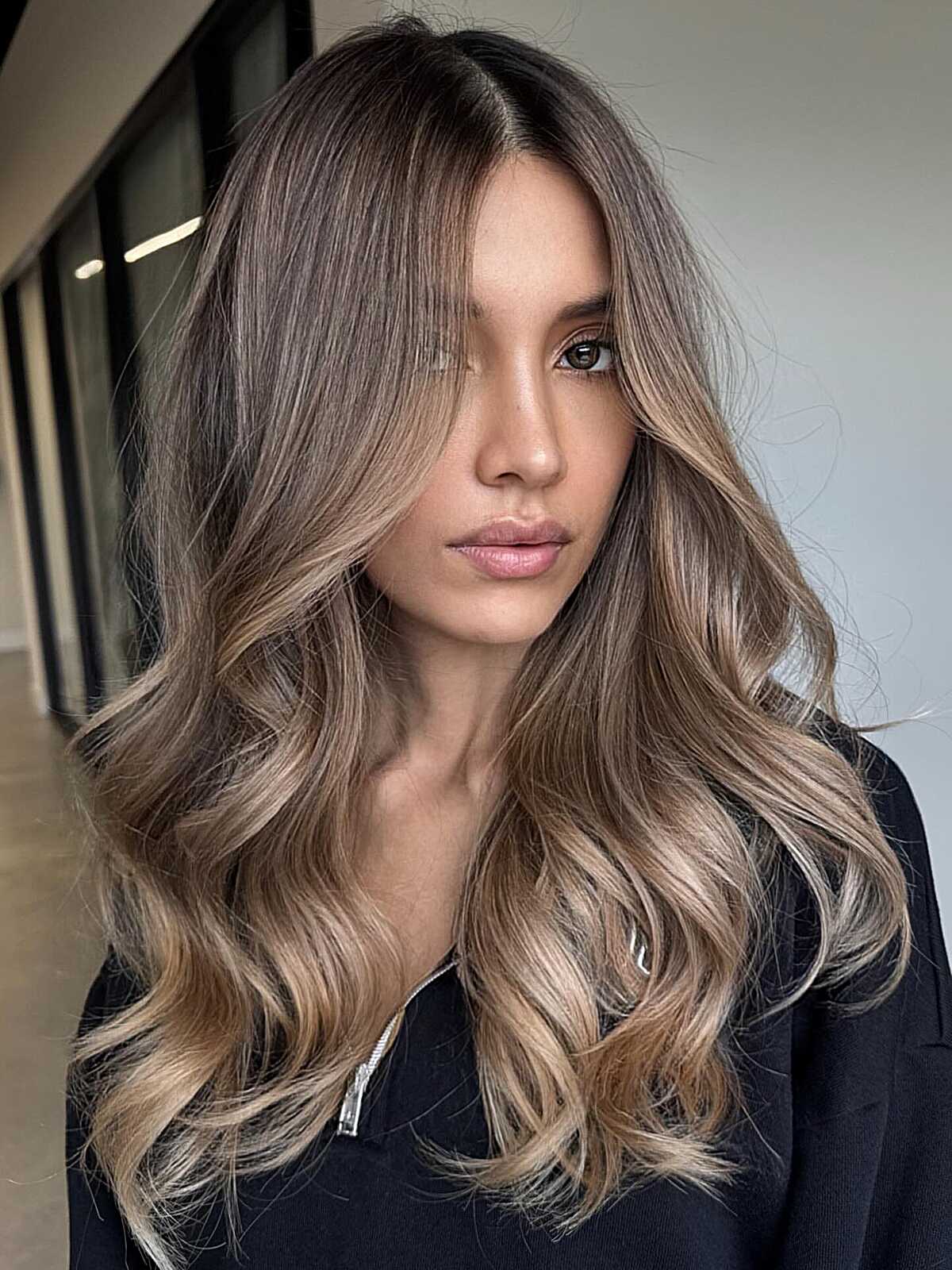 Long cool bronde hair with feathered ends and loose waves.