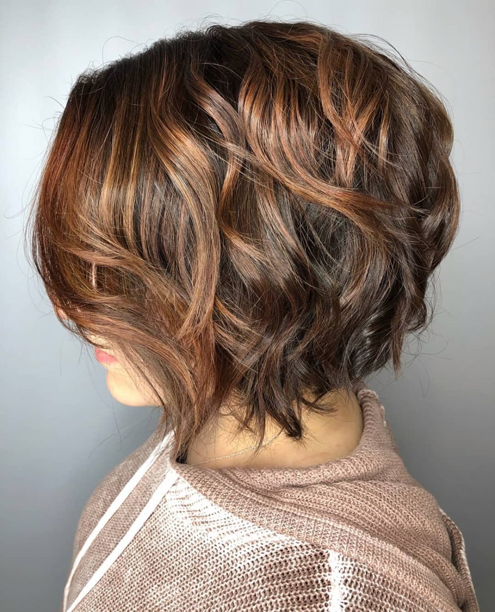Wavy stacked bob with warm brown highlights.