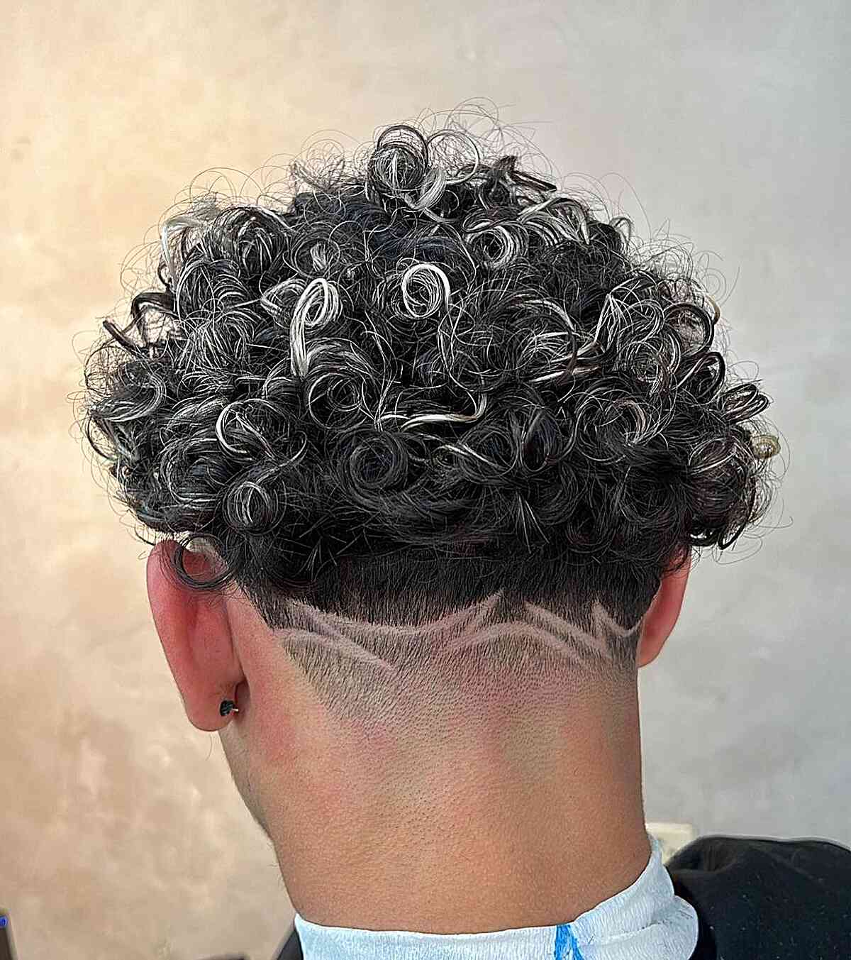 Curly top with silver strands and shaved nape design
