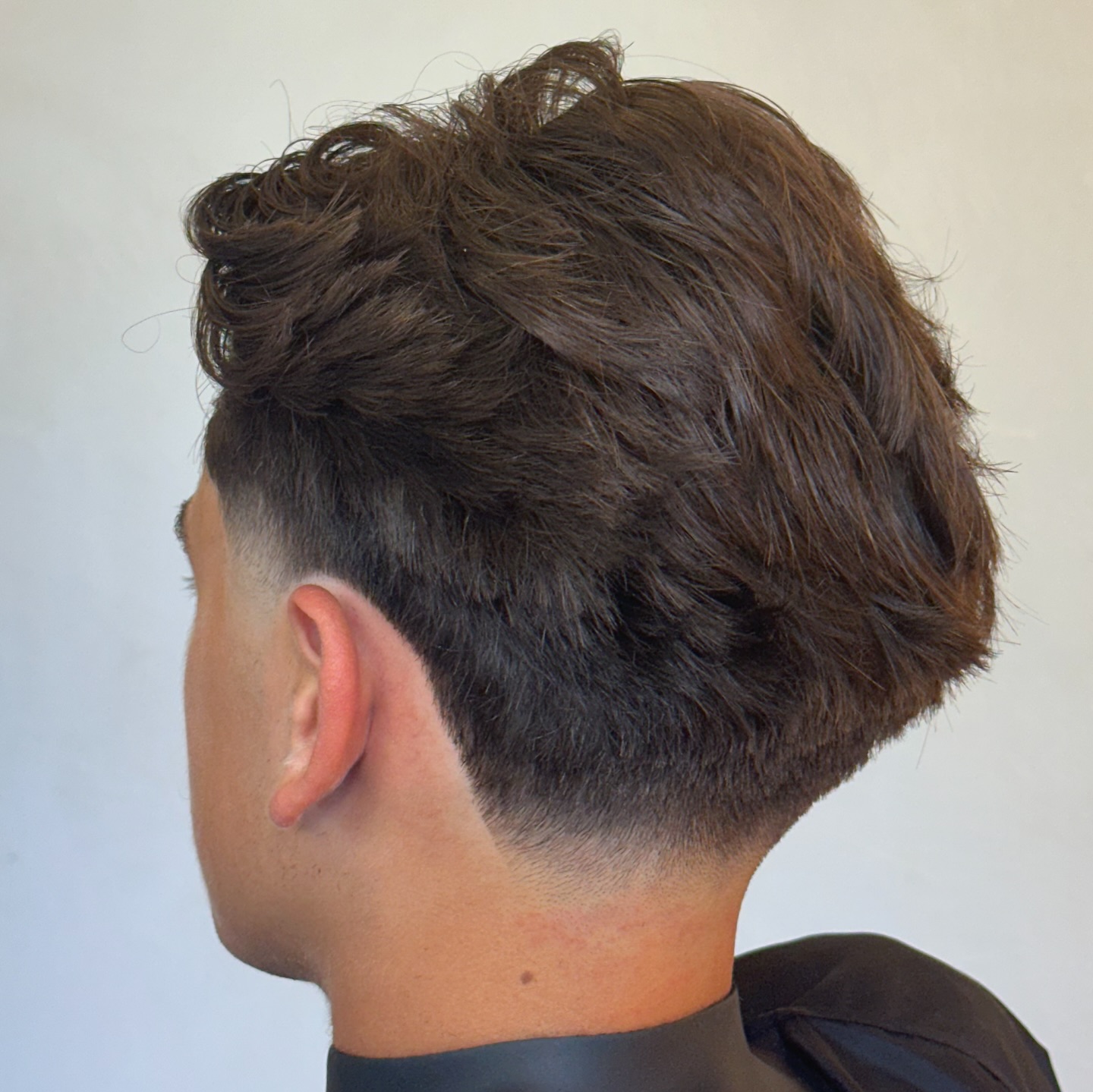Swept-back wavy top with taper fade at the sides.