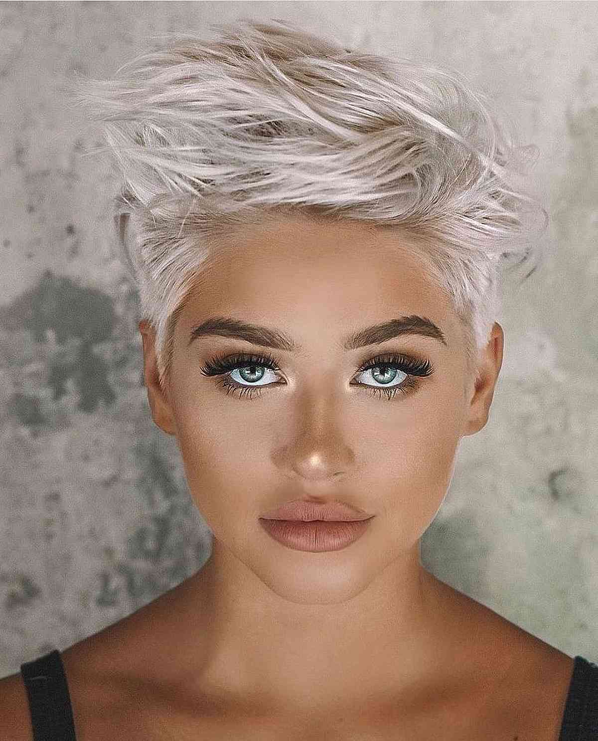 Tousled platinum pixie with airy top layers and short sides.