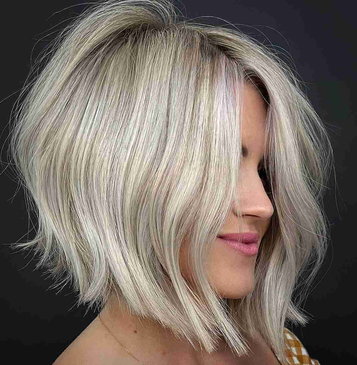 Blonde angled bob with slight waves and side-swept front layers.