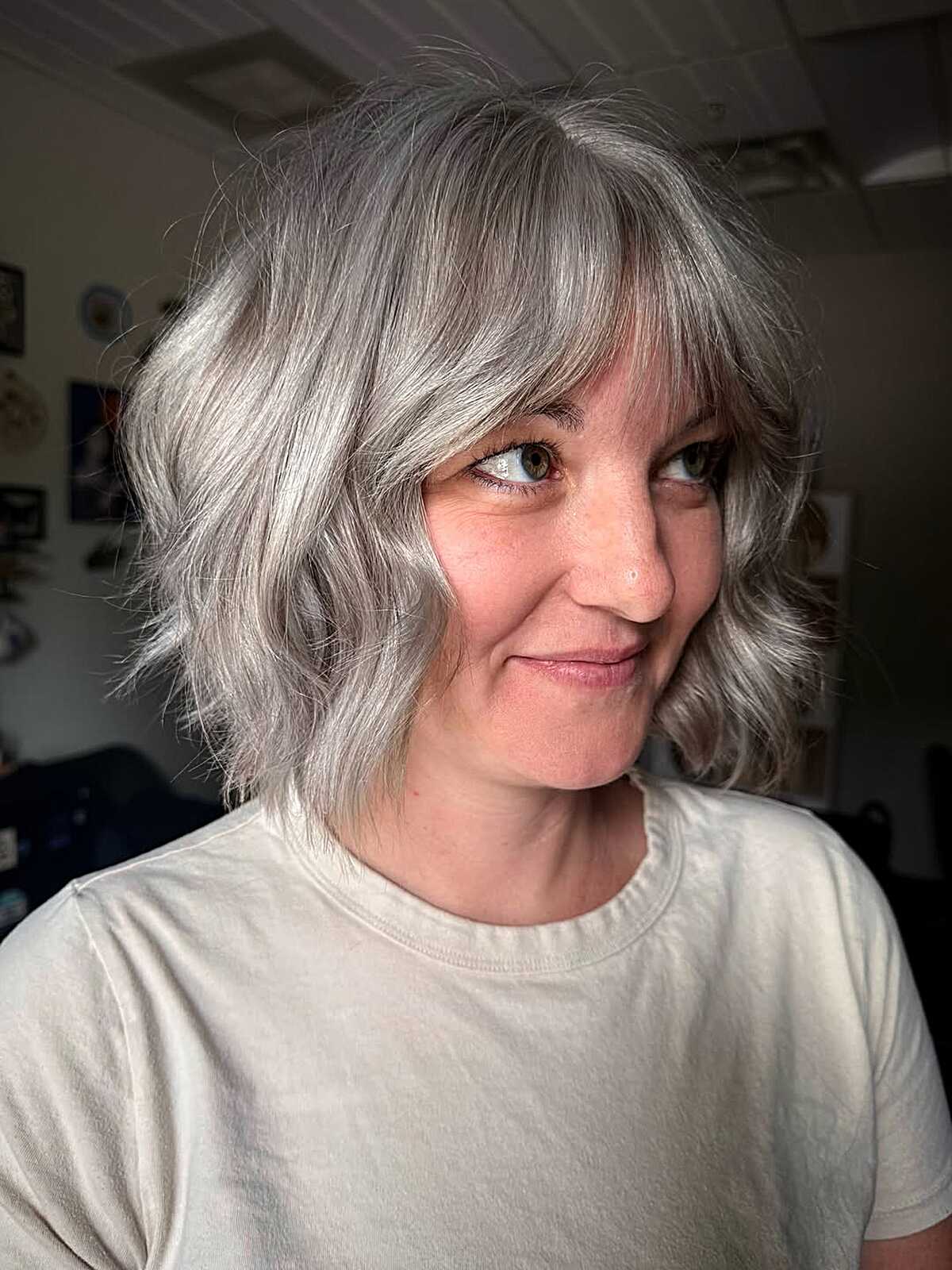 Wavy silver bob with curtain bangs and layered ends
