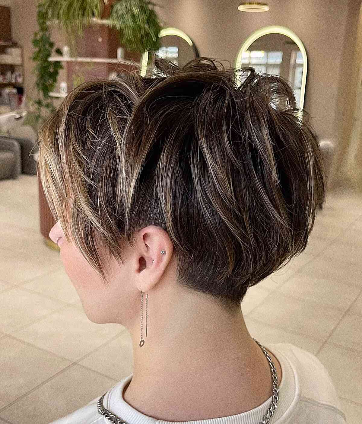 Tousled short cut with crown volume and exposed undercut sides.