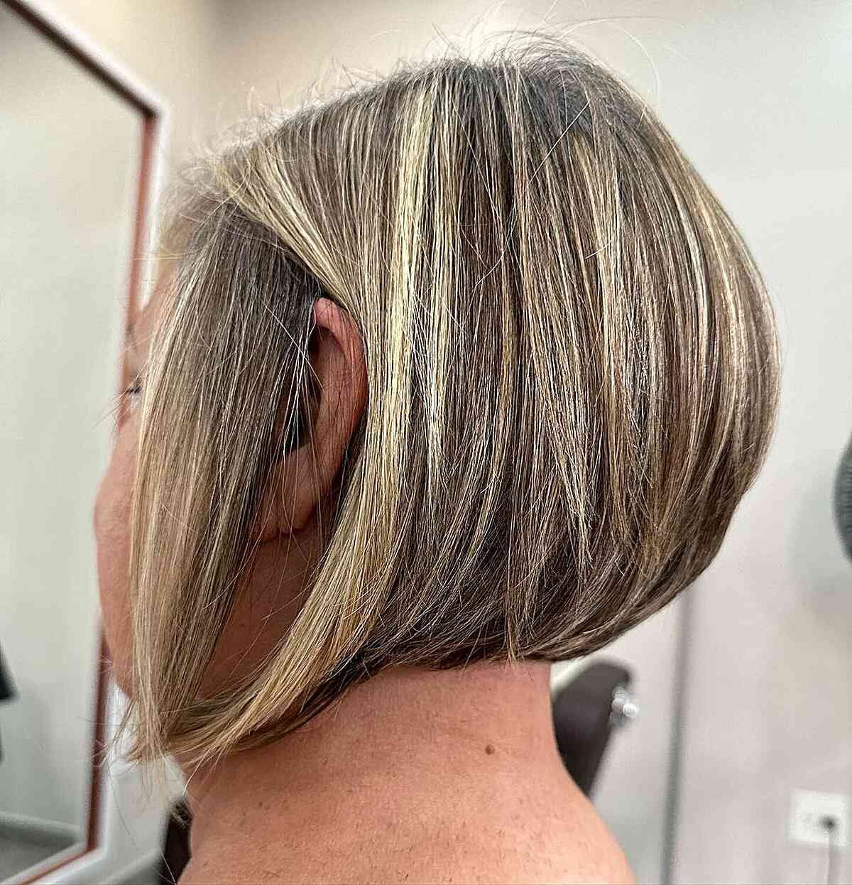 Short angled bob with blonde highlights and a smooth finish.